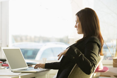 Side view of businesswoman working on laptop at desk