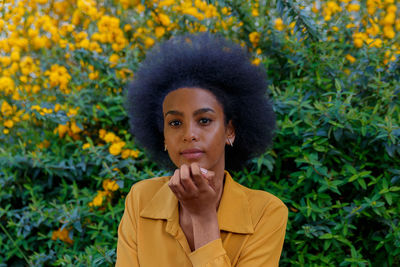 Portrait of woman with curly hair standing against yellow plants