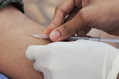 Cropped hands of doctor injecting patient in hospital