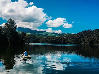 People sitting in lake against sky