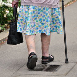Low section of senior woman walking with cane on street