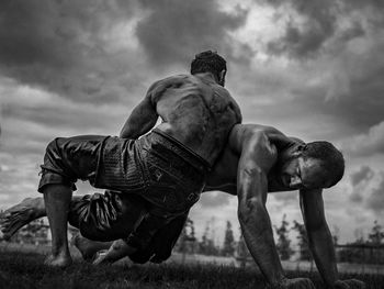 Full length of shirtless man on field against sky