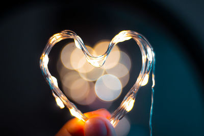 Close-up of hand holding heart shape illuminated lighting equipment