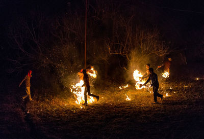 People by fire on field at night