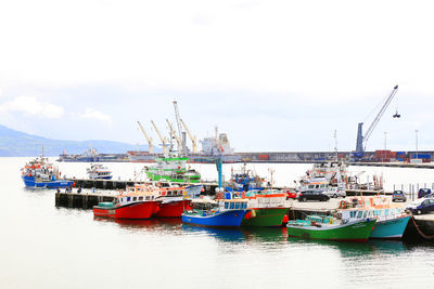 Boats moored at harbor against sky