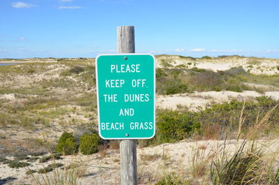 Green please keep off the dunes and beach grass sign