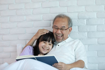 Cheerful grandfather telling story to granddaughter at home