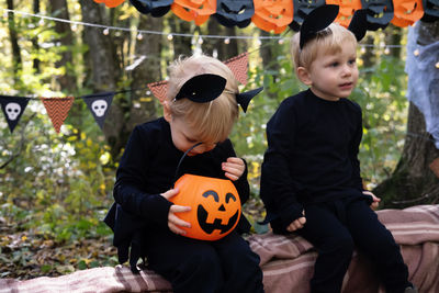 Two happy twins boys kids in halloween costumes having fun in halloween decorations outdoor