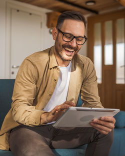 Young man using laptop while sitting on sofa at home