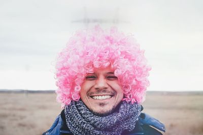 Portrait of smiling young woman against pink sky