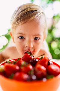 Baby girl sitting while eating strawberry at home