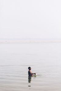 Rear view of man in lake against clear sky