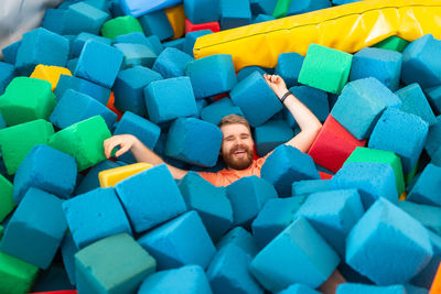 Full length of a young man sitting on colorful stack