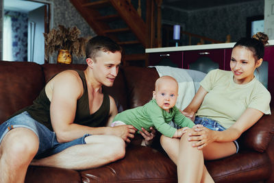 Portrait of happy family sitting on sofa at home