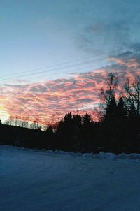 Scenic view of landscape against dramatic sky during sunset