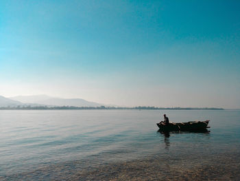 Man in boat sailing on sea against clear sky