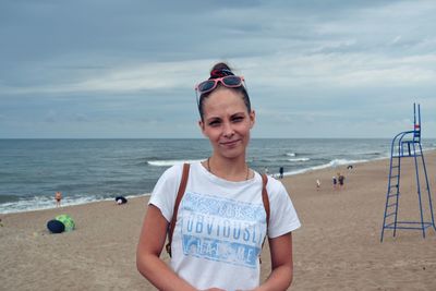 Portrait of woman standing at beach against sky