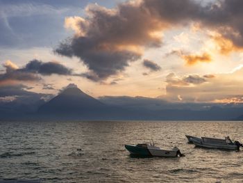 Sailboats moored on sea against sky during sunset