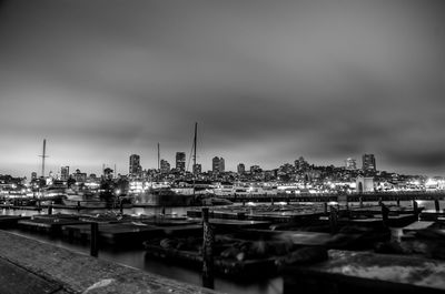 Boats moored at harbor against sky in city