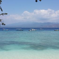 Boats in sea against cloudy sky