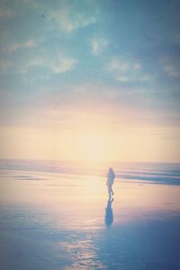 Silhouette man standing on beach against sky during sunset