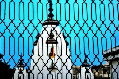 Historic temple against clear blue sky seen through silhouette fence