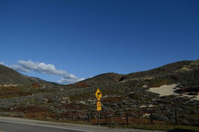 Road by mountain against blue sky