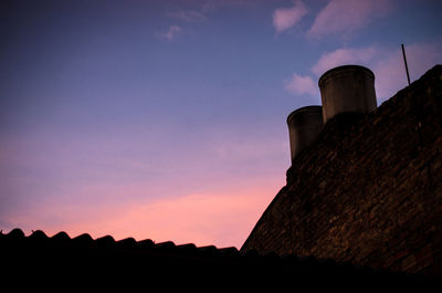 Low angle view of silhouette house against sky during sunset