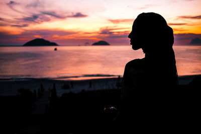 Silhouette woman on beach against sky during sunset