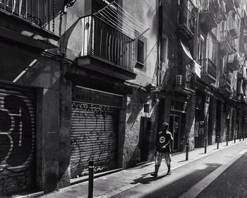 Full length of man walking on street amidst buildings in city