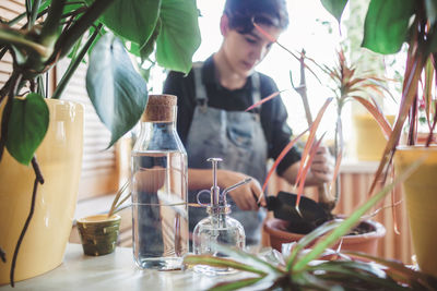 Happy young girl repotting home plants on the balcony, green environment in room, home gardening