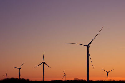 Windmills on silhouette landscape against sky during sunset