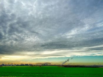 Scenic view of grassy field against cloudy sky