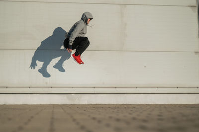 Side view of man skateboarding on sidewalk