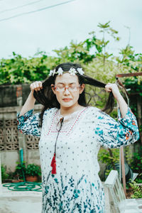 Portrait of young woman standing against plants