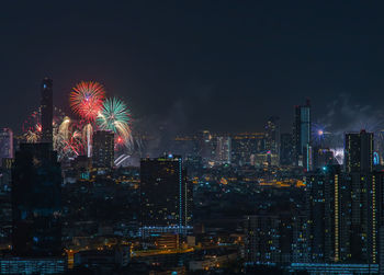 Firework display in city against sky at night