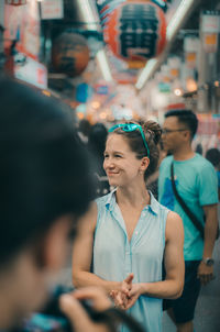 Smiling woman looking away while standing in crowd