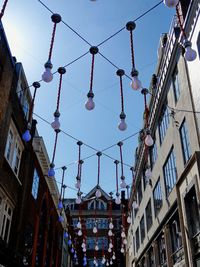 Low angle view of lanterns hanging by buildings against sky