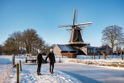 People on field against clear sky during winter