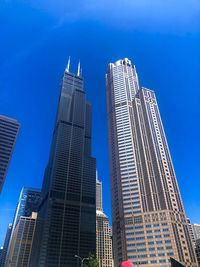 Low angle view of skyscrapers against blue sky