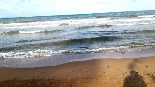 View of calm beach against cloudy sky