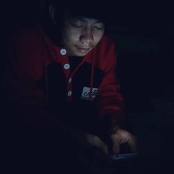 Portrait of boy using mobile phone in darkroom