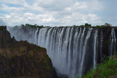 Scenic view of waterfall against sky