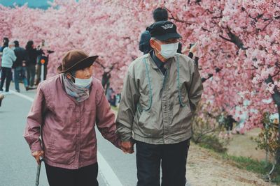 Rear view of man and woman walking on cherry blossom