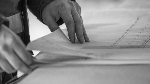 Midsection of male architect with blueprint at desk