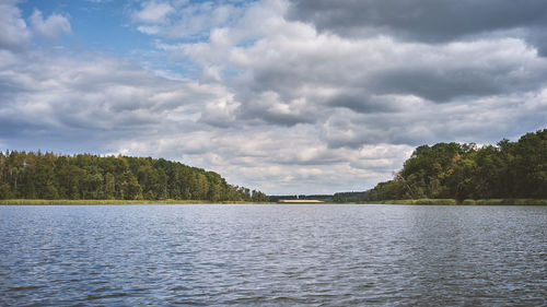 Cloudy summer weather at a lake in the middle of a dense forest.