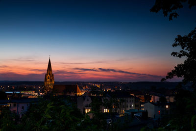Illuminated buildings in city against sky at sunset