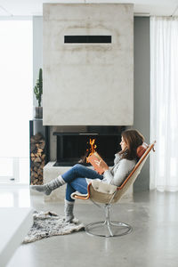Woman reading book in front of fireplace