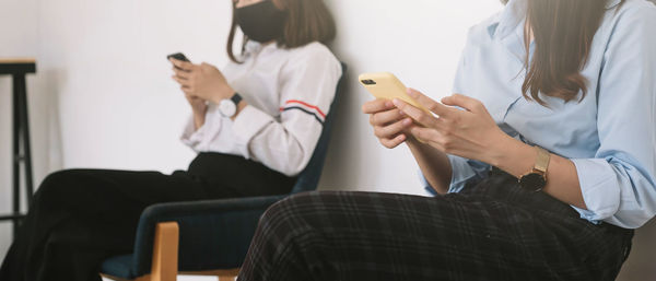 Midsection of woman using mobile phone while sitting on chair
