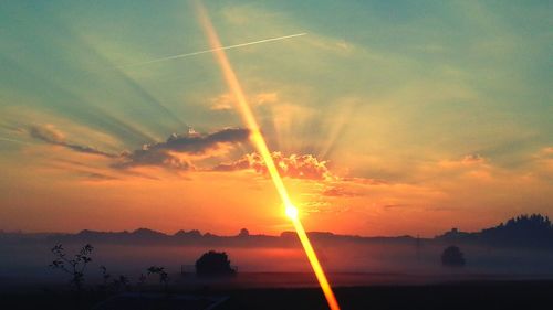 Sun shining through clouds over landscape